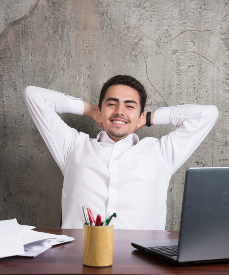 Smiling employee with sheets of papers and sitting at the desk Image description